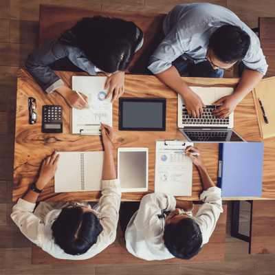 There are 3 men and 1 women working on laptops and document gathered on a meeting. They are sitting at the table with pens in their hands. There are 3 men and 1 women working on laptops and document gathered on a meeting. They are sitting at the table with pens in their hands.