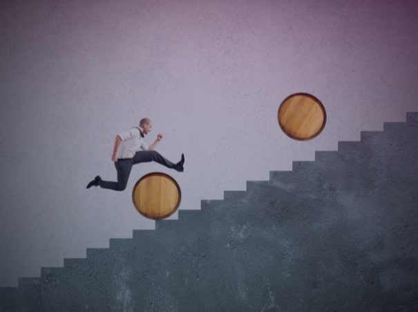 Businessman jumping over barrels on a staircase