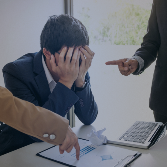 a man covering his face in an office and a woman and a man pointing fingers at him and his work, he looks under pressure and looks like a conflict in a office
